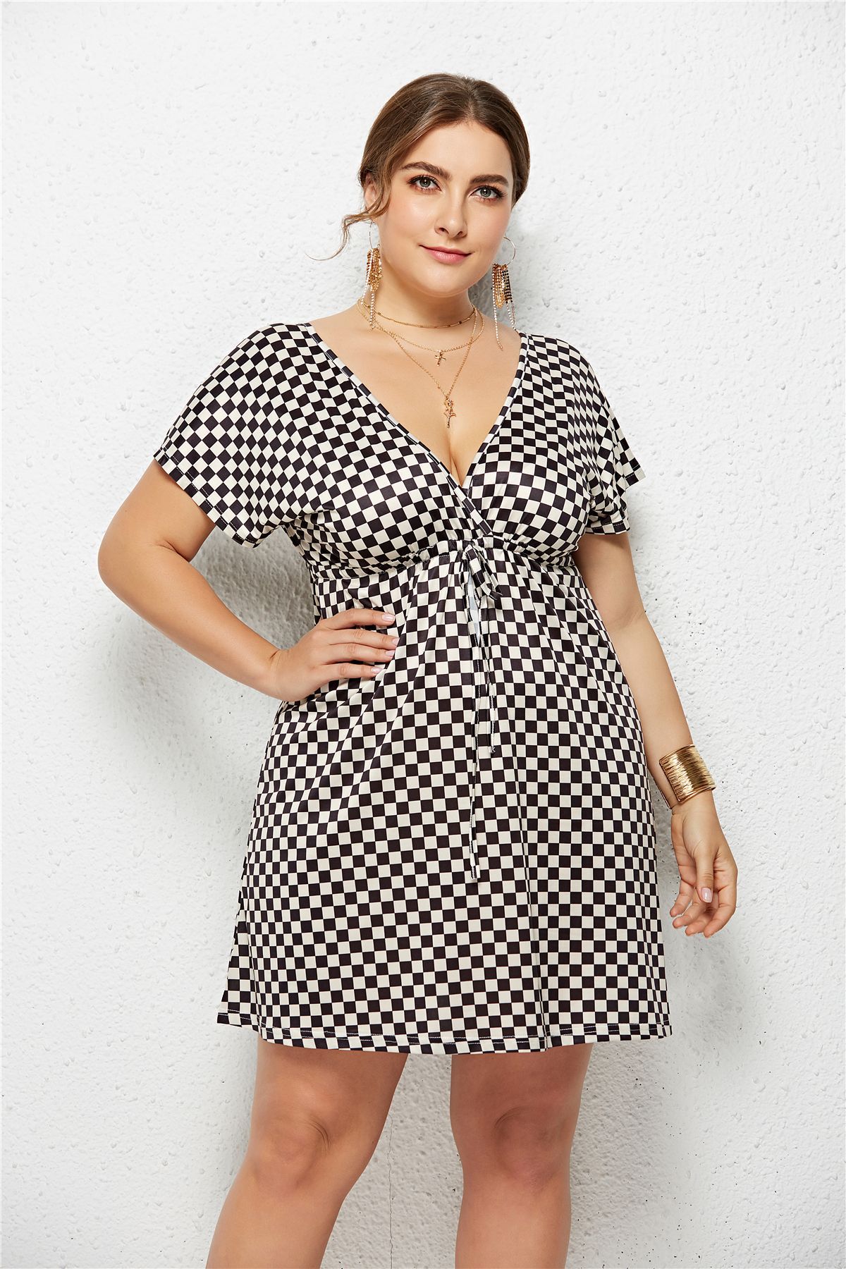 Woman wearing a black and white checkered dress against a plain background