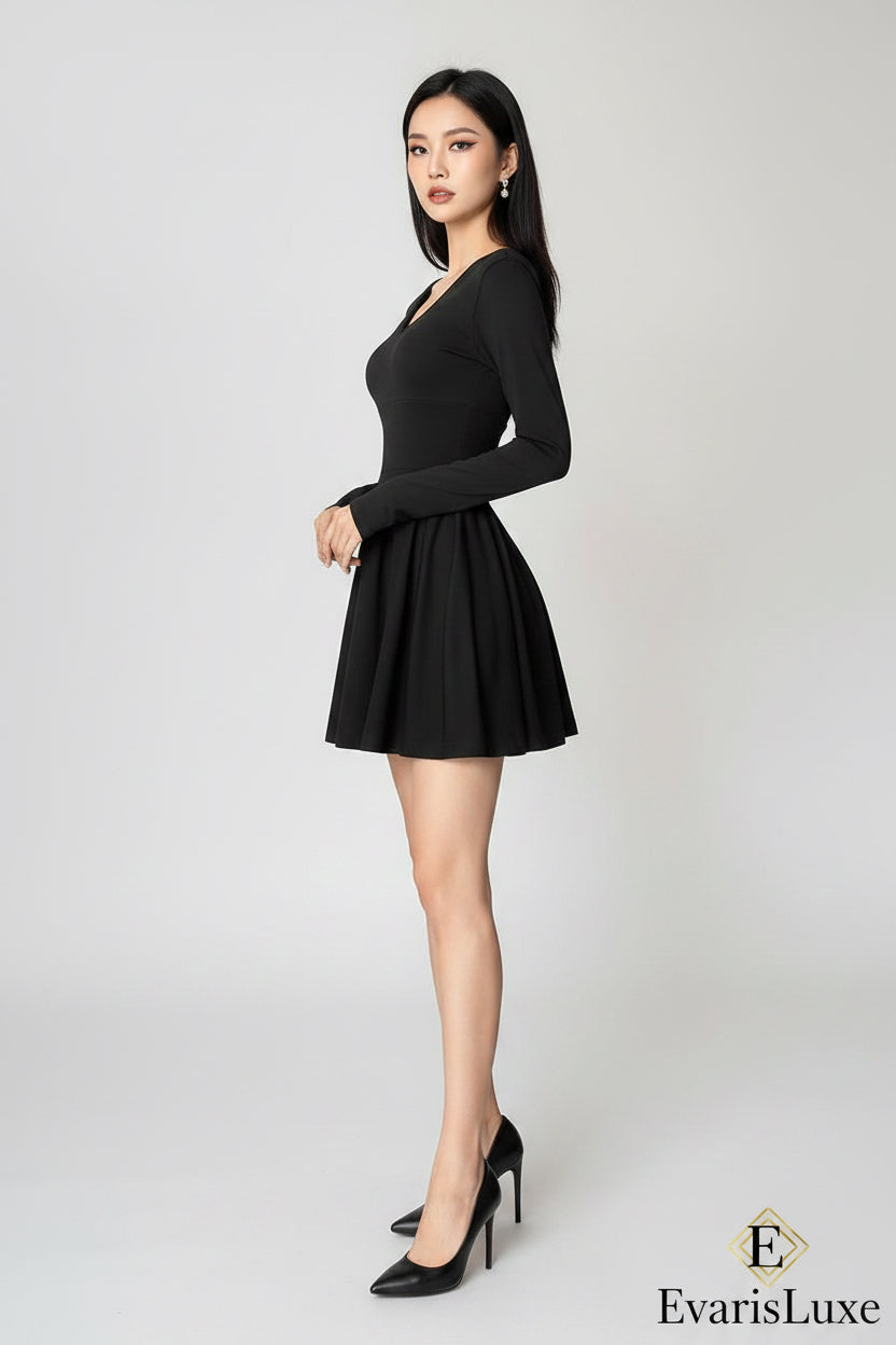 Person wearing a black dress standing in a room with a white wall and a table.