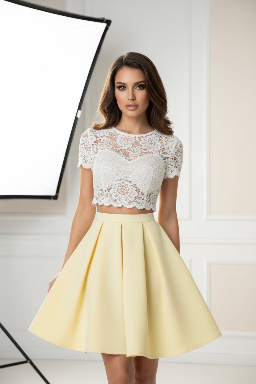 Woman taking a mirror selfie wearing a white top and yellow skirt.