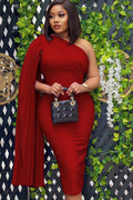 Woman in a red dress holding a blue handbag against a decorative background