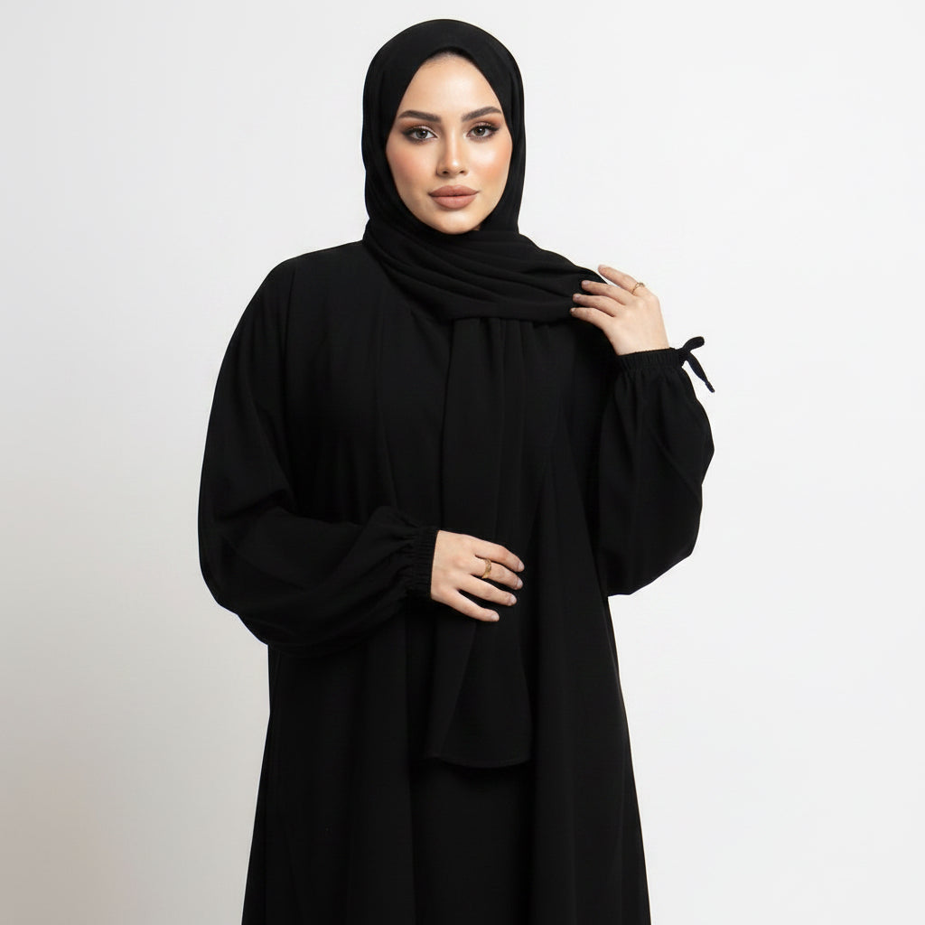 Black abaya being held by a person on a white background