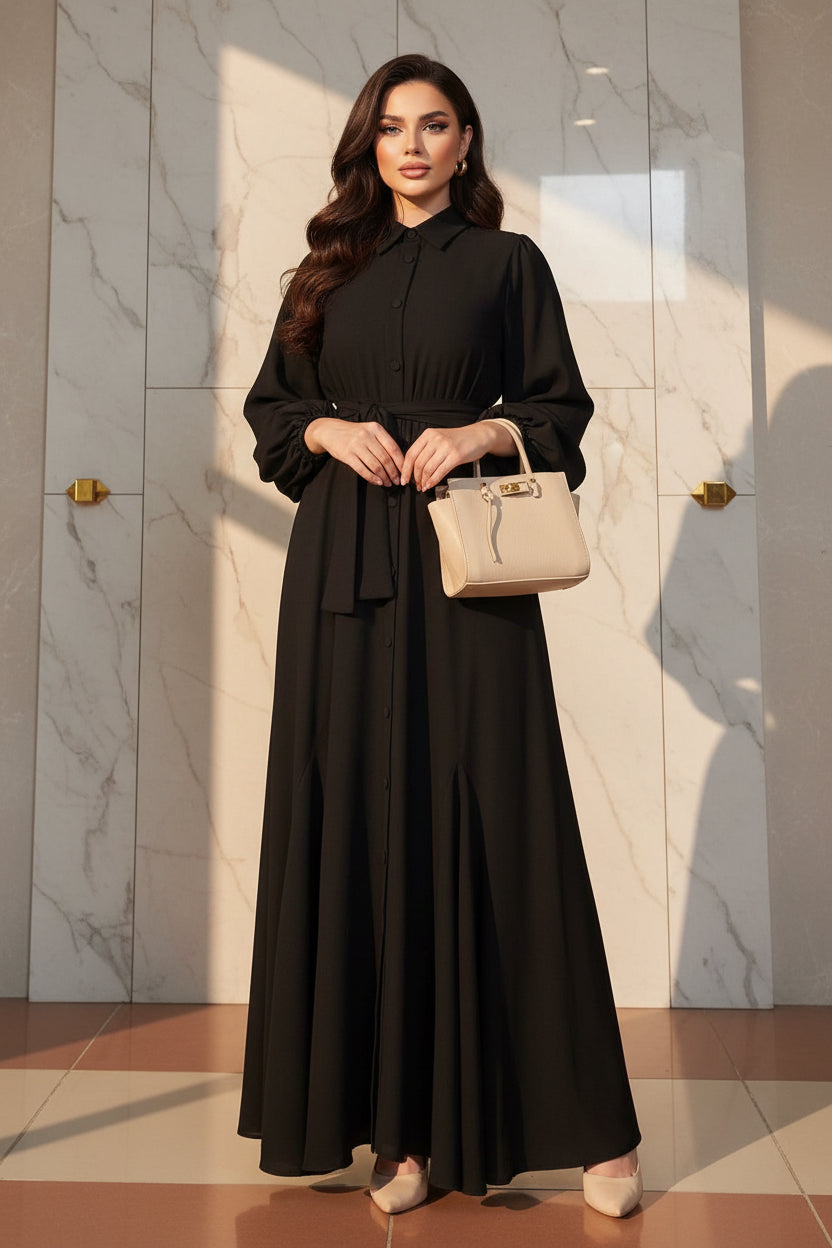 Person wearing a black dress holding a beige handbag in a room with shelves and decor.