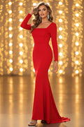 Woman in a red evening gown standing on a balcony with a forest background