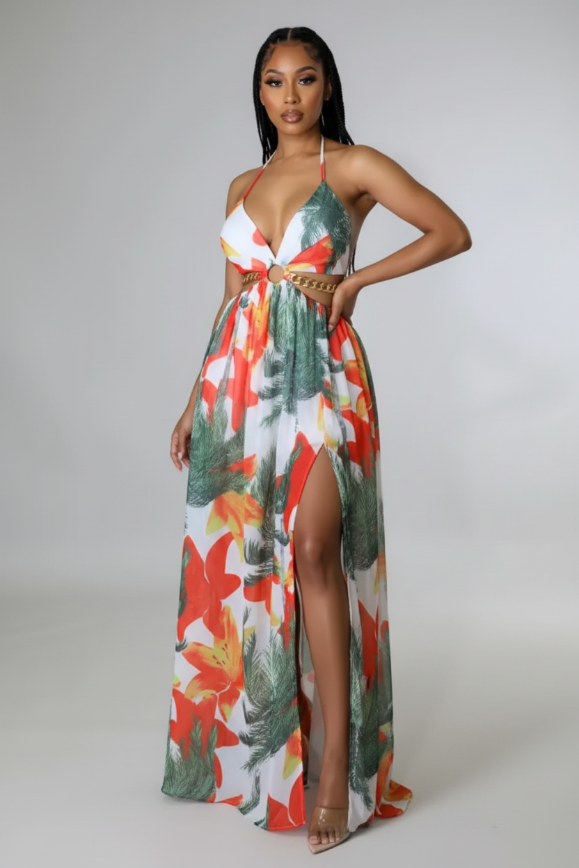 Woman wearing a colorful floral dress with a high slit on a plain background