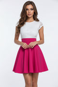 Woman taking a mirror selfie wearing a white top with lace details and a pink skirt.