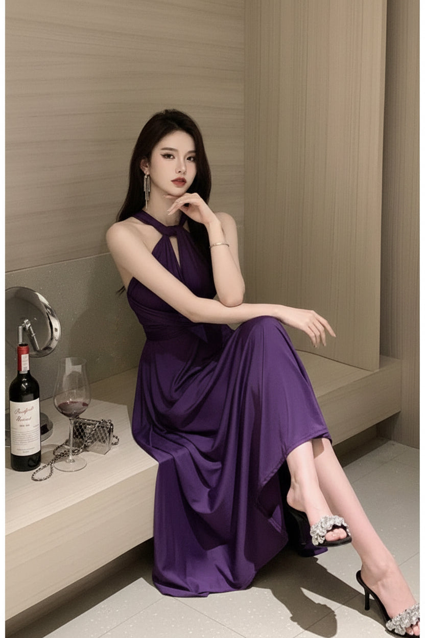 Woman in a purple dress sitting on a bench with a bottle of wine and glasses.