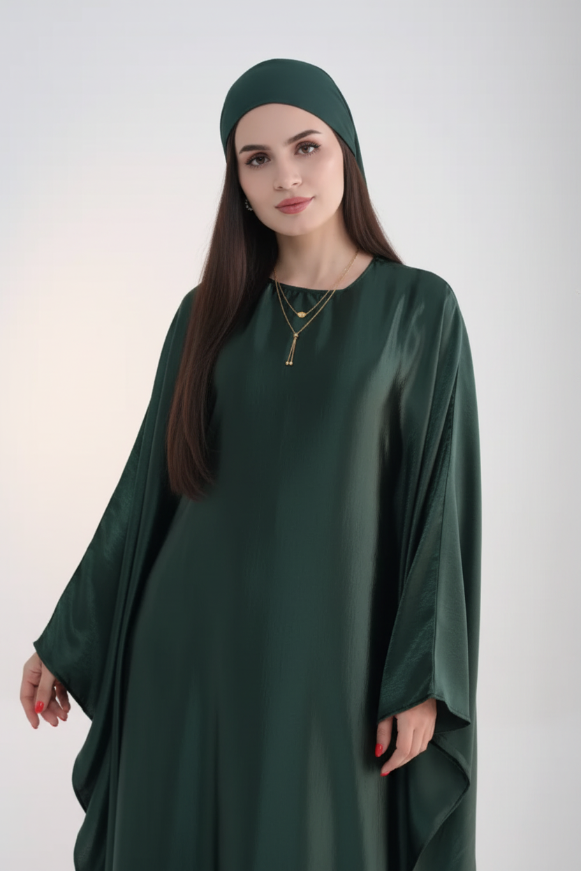 Woman wearing a dark green abaya with sunglasses on her head against a white background