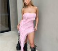 Woman wearing a pink strapless dress with black high-heeled boots indoors.