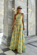 Woman in a yellow floral dress standing in front of a marble wall.