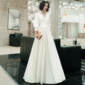 Woman in a white dress standing in an indoor setting with modern decor.