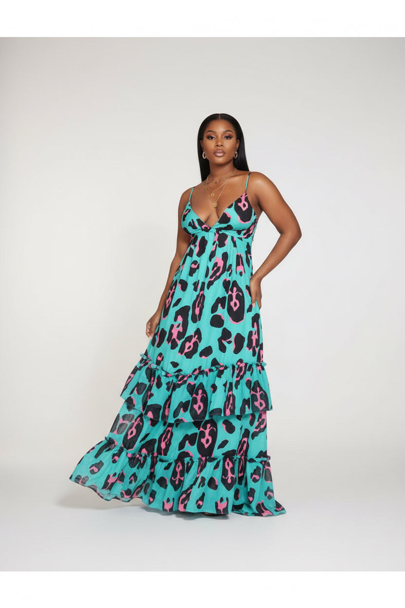 Woman wearing a turquoise dress with pink and black leopard print in an indoor setting.