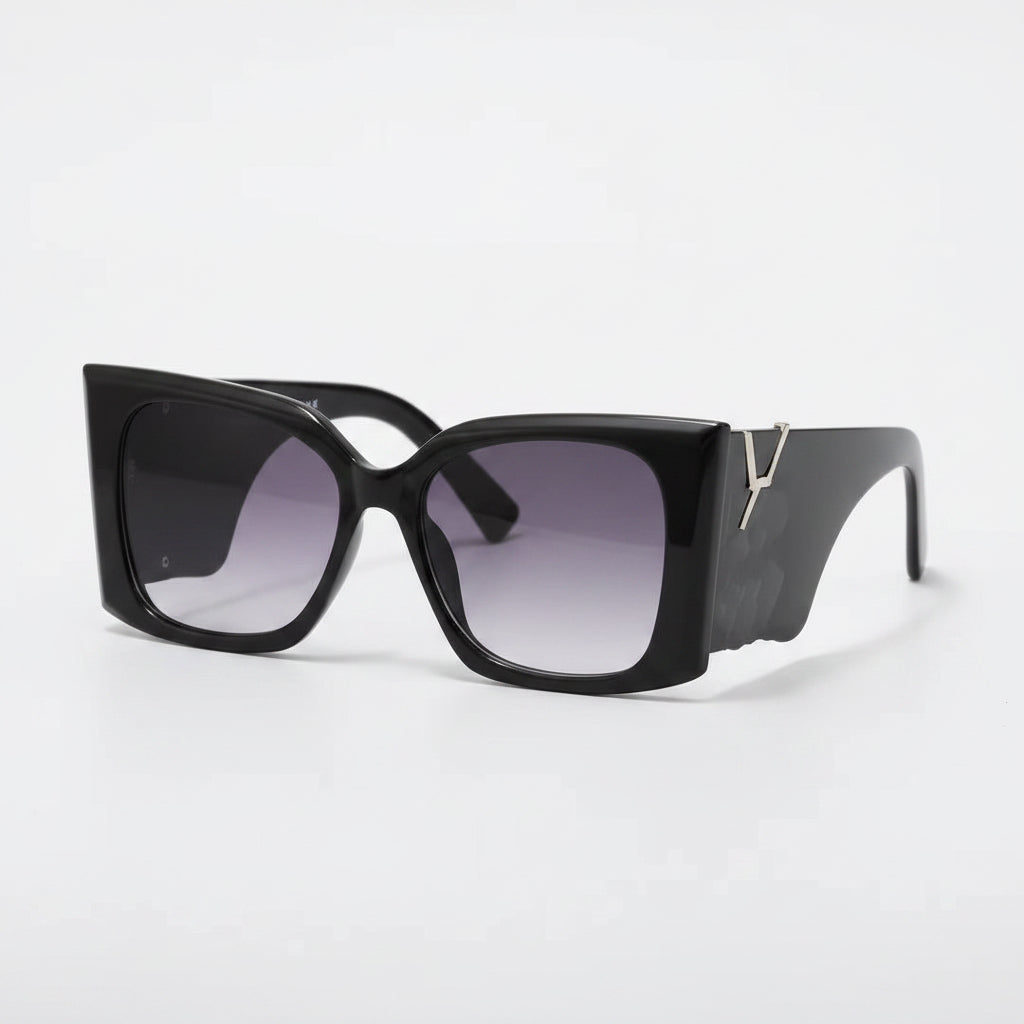 Black sunglasses with gradient lenses on a white surface with a black case and gold tag.