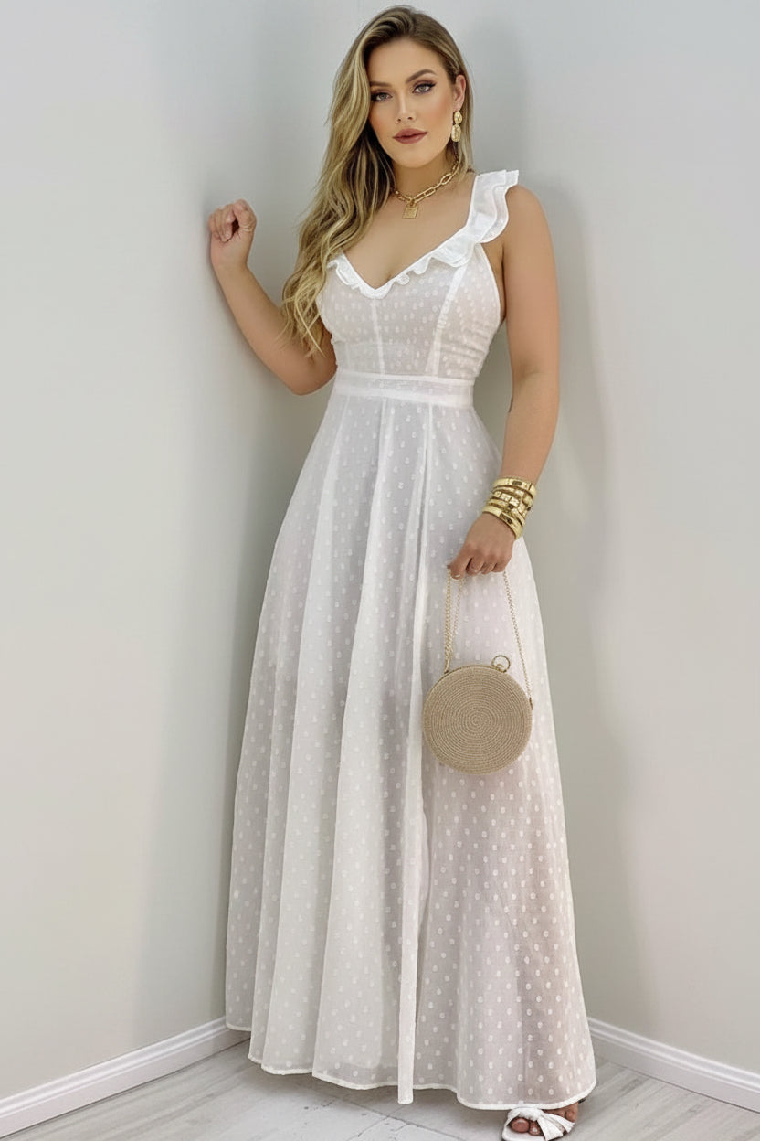 Woman wearing a white polka dot dress holding a round beige handbag against a plain background