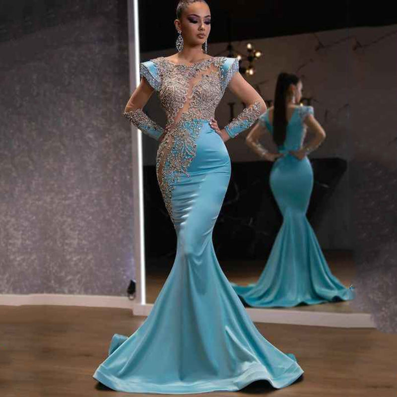 Woman wearing a blue evening gown with intricate detailing in front of a mirror.