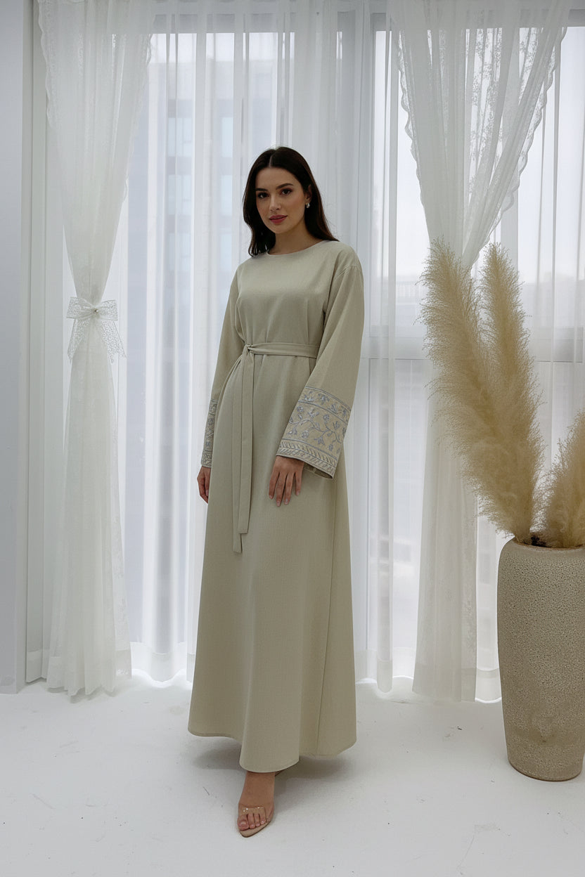 Beige dress on a mannequin with decorative elements in a softly lit room.