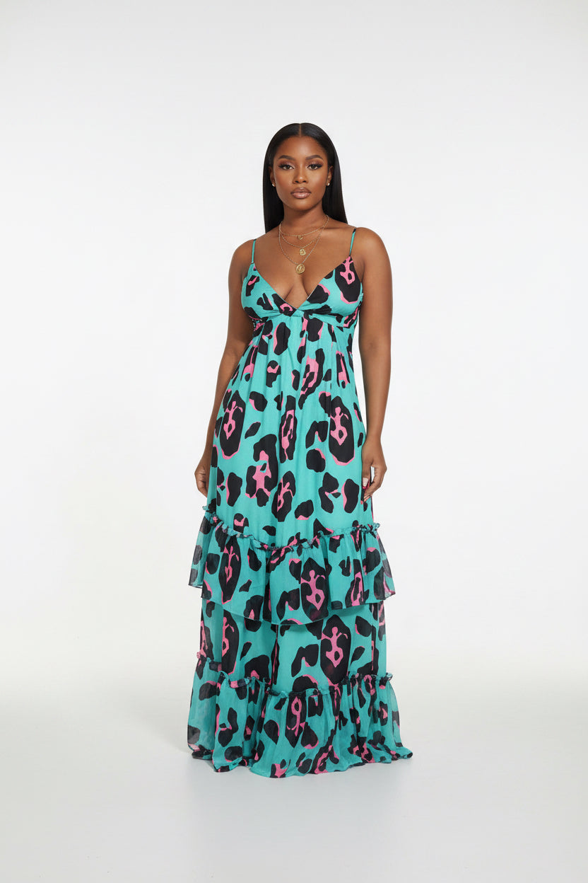 Woman wearing a turquoise dress with pink and black leopard print in an indoor setting.