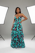 Woman wearing a turquoise dress with pink and black leopard print in an indoor setting.