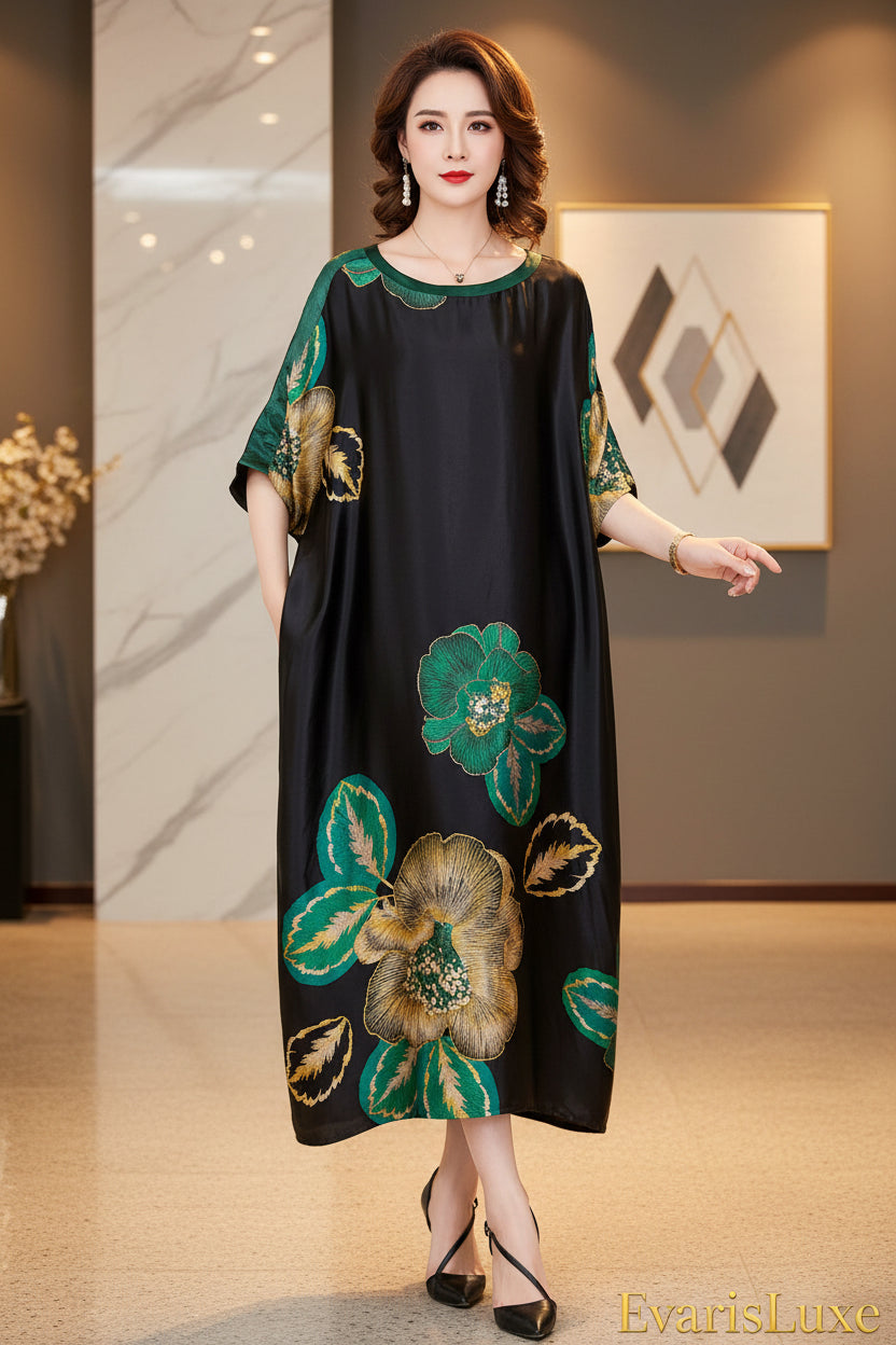 Woman wearing a black dress with green floral embroidery against a gray wall.
