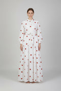 White dress with red polka dots worn by a person against a plain background