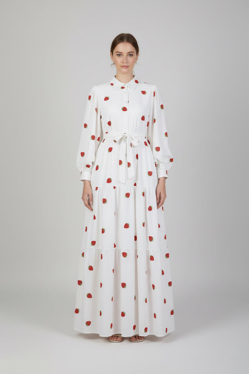 White dress with red polka dots worn by a person against a plain background