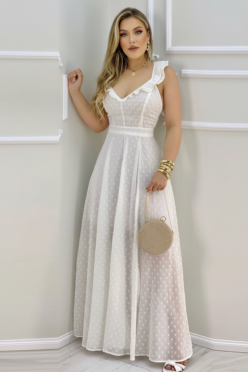 Woman wearing a white polka dot dress holding a round beige handbag against a plain background