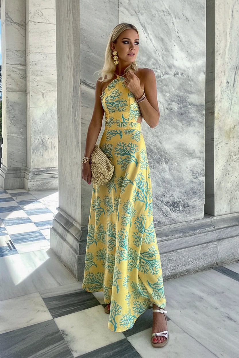 Woman in a yellow floral dress standing in front of a marble wall.