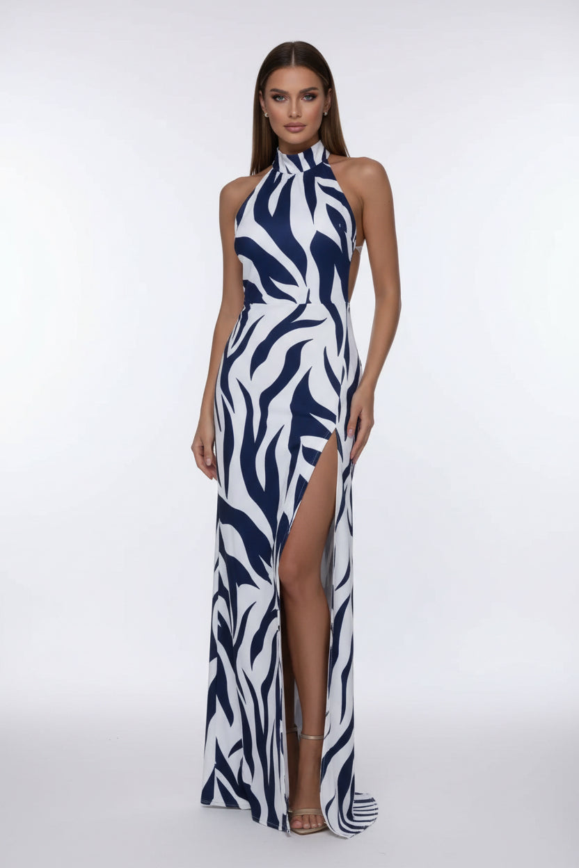 Woman wearing a zebra print dress with a high slit against a gray wall.