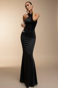 Woman in a black evening gown standing on a staircase holding a glass of wine.
