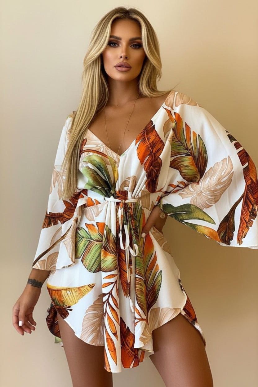 Woman wearing a tropical leaf patterned dress against a neutral background