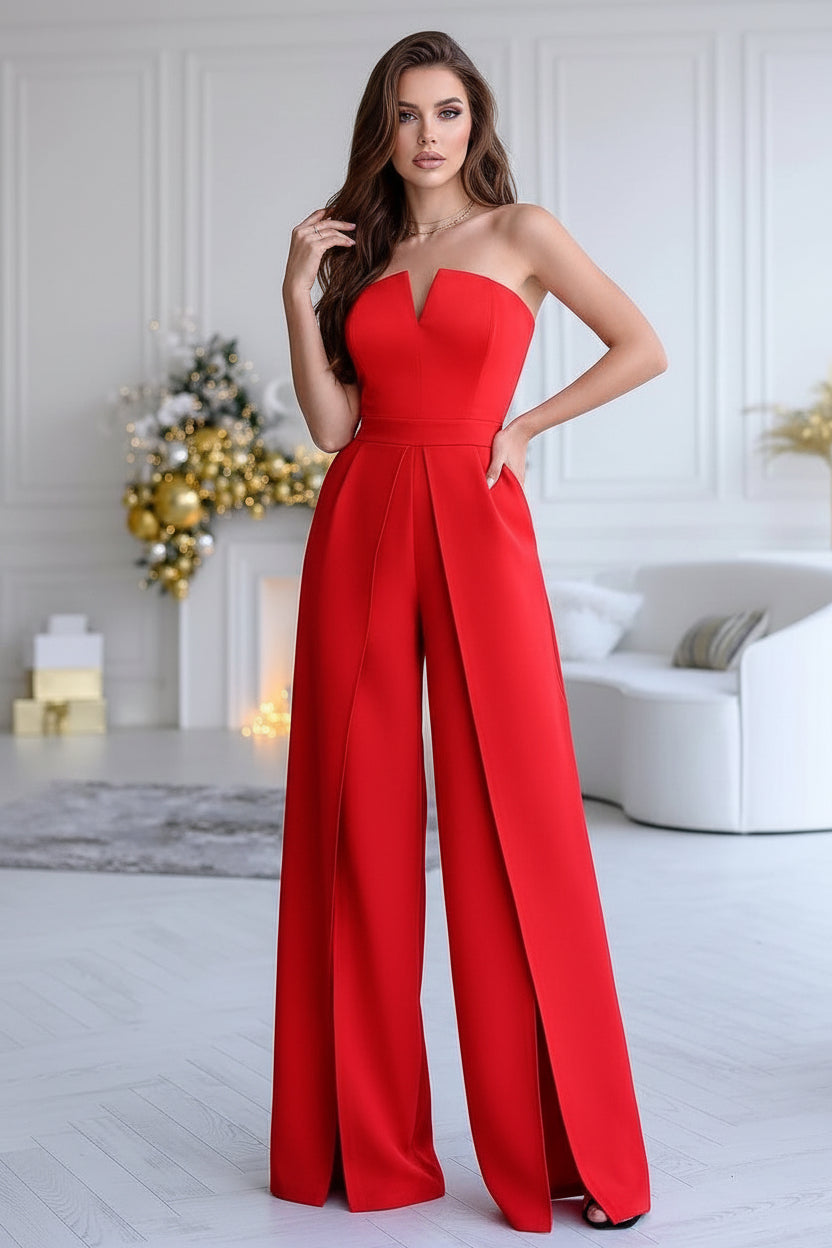 Red strapless jumpsuit worn by a model in a stylish room with decorative elements.