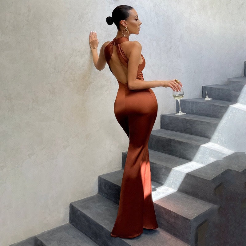 Woman in a long brown dress standing on stone steps holding a glass of wine.