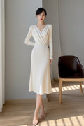Person wearing a white dress taking a mirror selfie in a room with a window and chair.