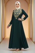 Woman wearing a dark green dress with gold embroidery in an outdoor setting.