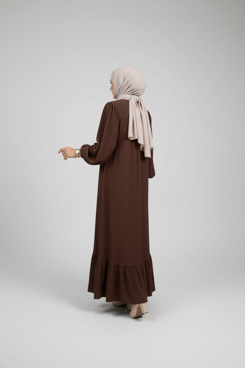 Person wearing a brown dress in a minimalistic room.