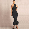 Woman wearing a black dress with ruffled bottom section on a beige background