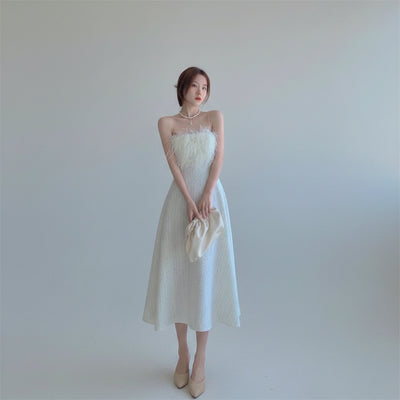Woman in a white dress standing in a modern living room.