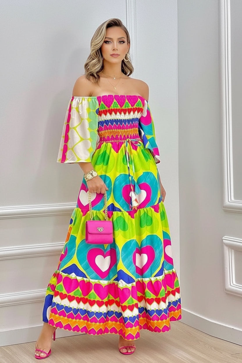 Woman wearing a colorful off-shoulder dress with heart patterns in a room.