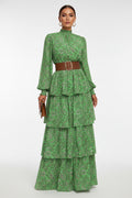 Person wearing a green floral dress with a brown belt on a sidewalk.
