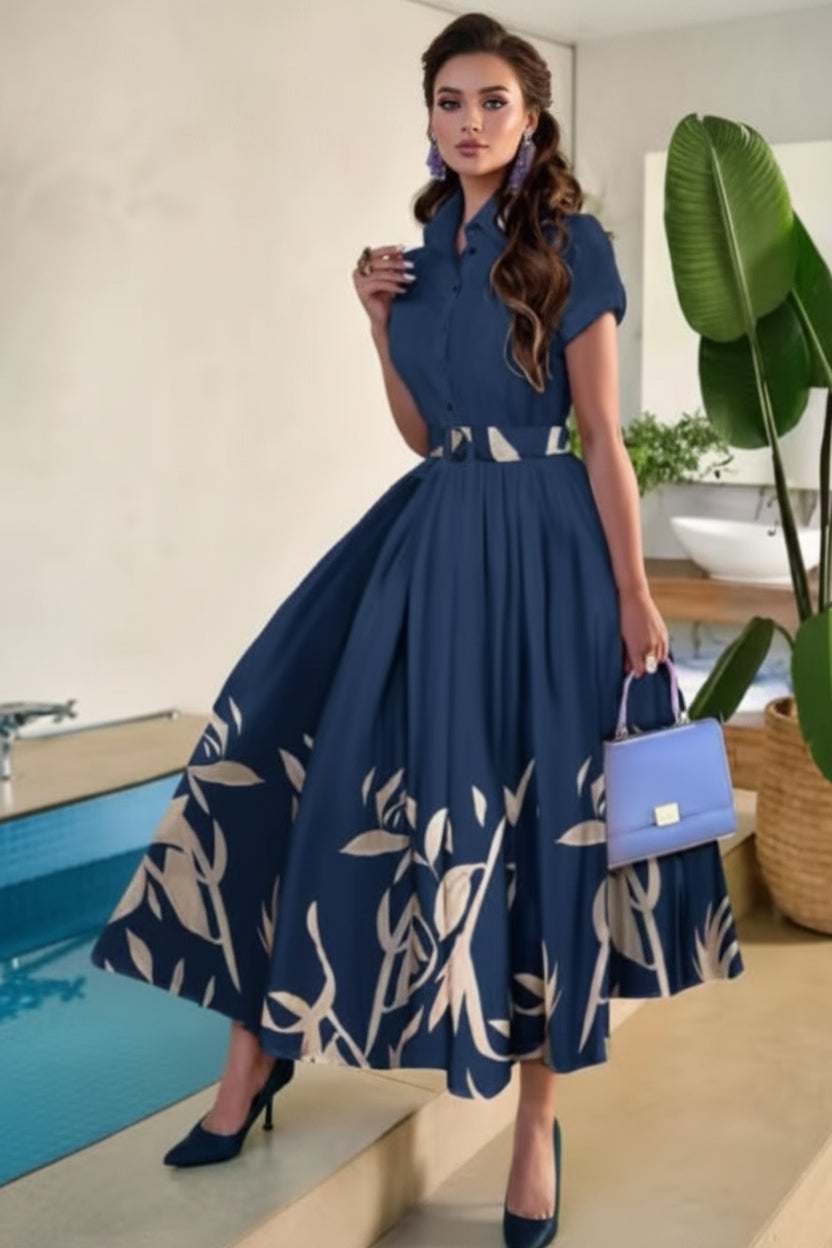 Woman in a blue dress with a floral pattern holding a blue handbag by a pool.