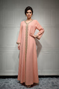 Peach-colored dress with gold embroidery on a mannequin against a white paneled wall.