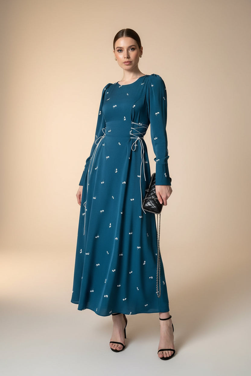 Woman wearing a blue dress with white patterns against a neutral background