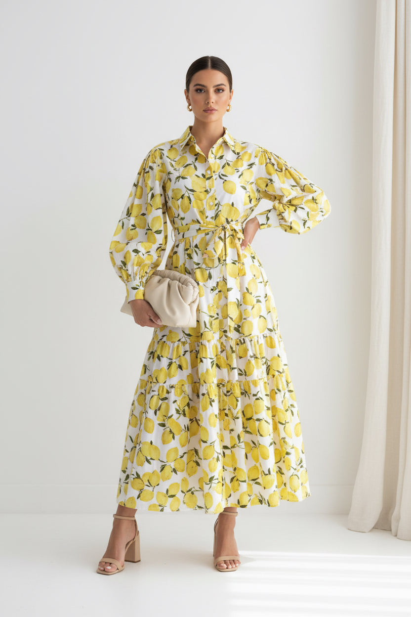 Woman wearing a white dress with yellow pineapple patterns against a plain background