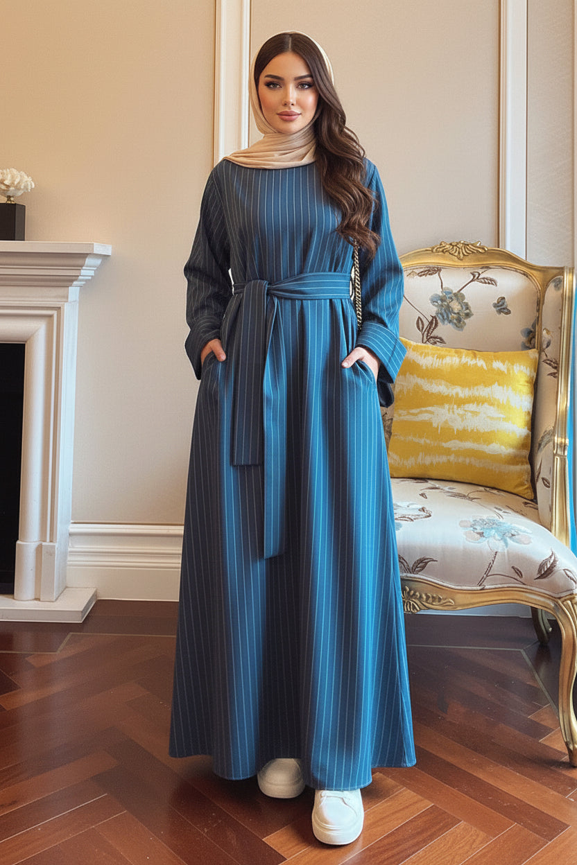 Person wearing a blue dress standing in a room with a fireplace and decorative chair.
