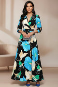 Woman wearing a black floral dress with blue and green flowers on a white background