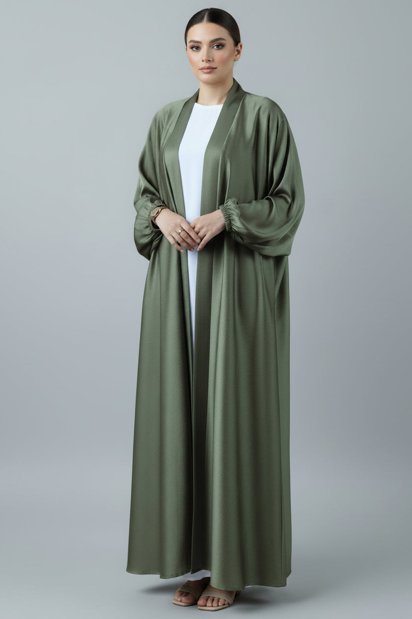 Person wearing a green cardigan over a white shirt against a brick wall.