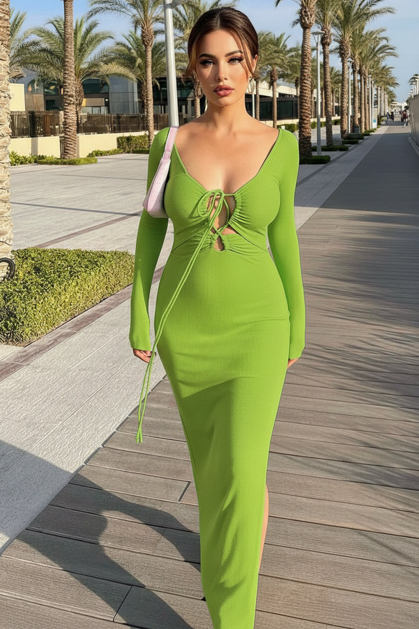 Woman in a green dress walking on a sidewalk with palm trees in the background