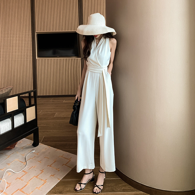 Woman in a white outfit and large hat standing in a modern room.